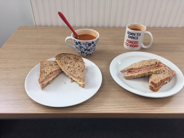 2 plates with sandwiches and cups of tea on a table