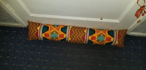A multi-coloured draft excluder in front of a door