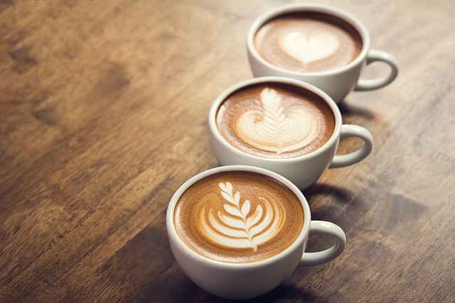 A row of three lattes. Each with a latte art design