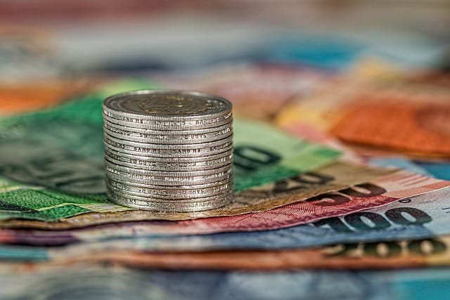 A close up of a stack of coins on top of bills laid out on a surface