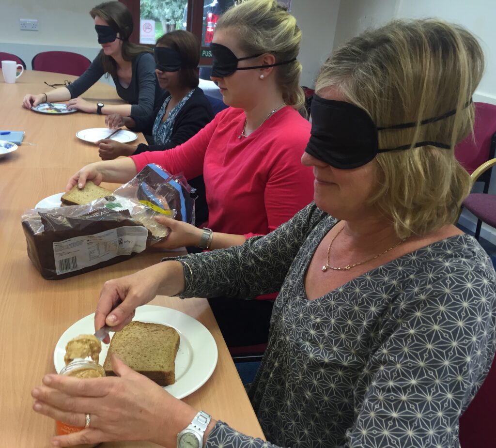 four people making sandwiches with blindfolds on