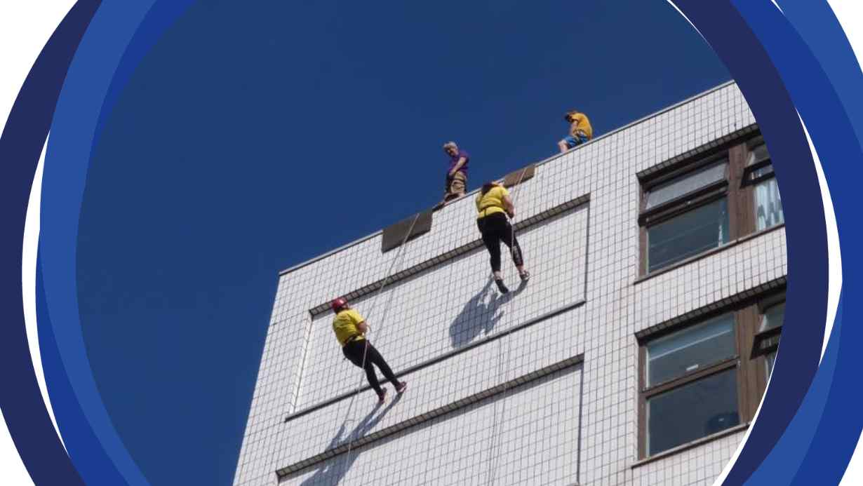 A ground view of 2 people abseiling a building