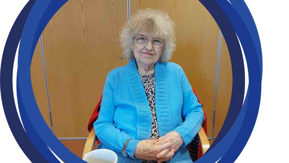 A photo of Jean sitting behind a table and posing for a photo.