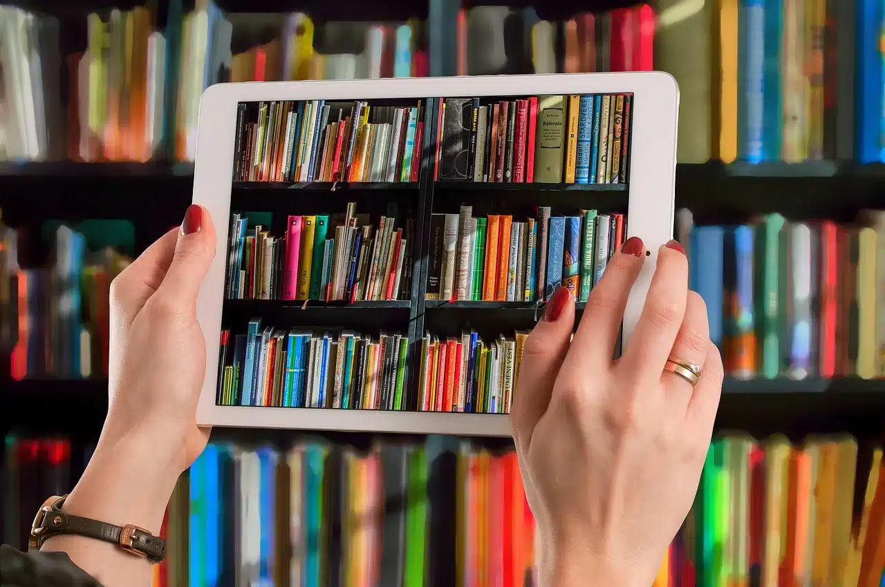 A person holding up an iPad to a bookshelf