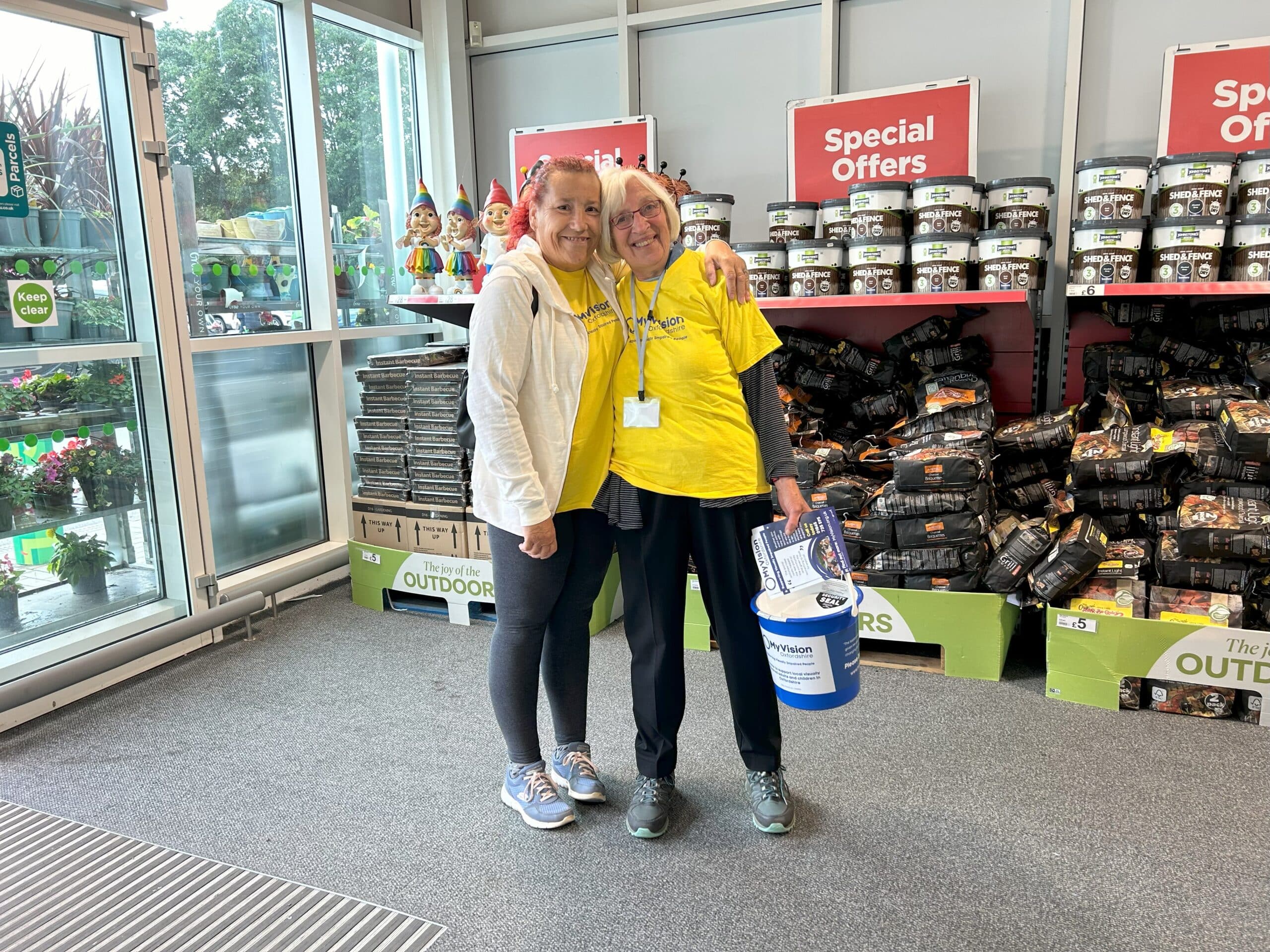 two women smiling, while holding collection buckets at ASDA