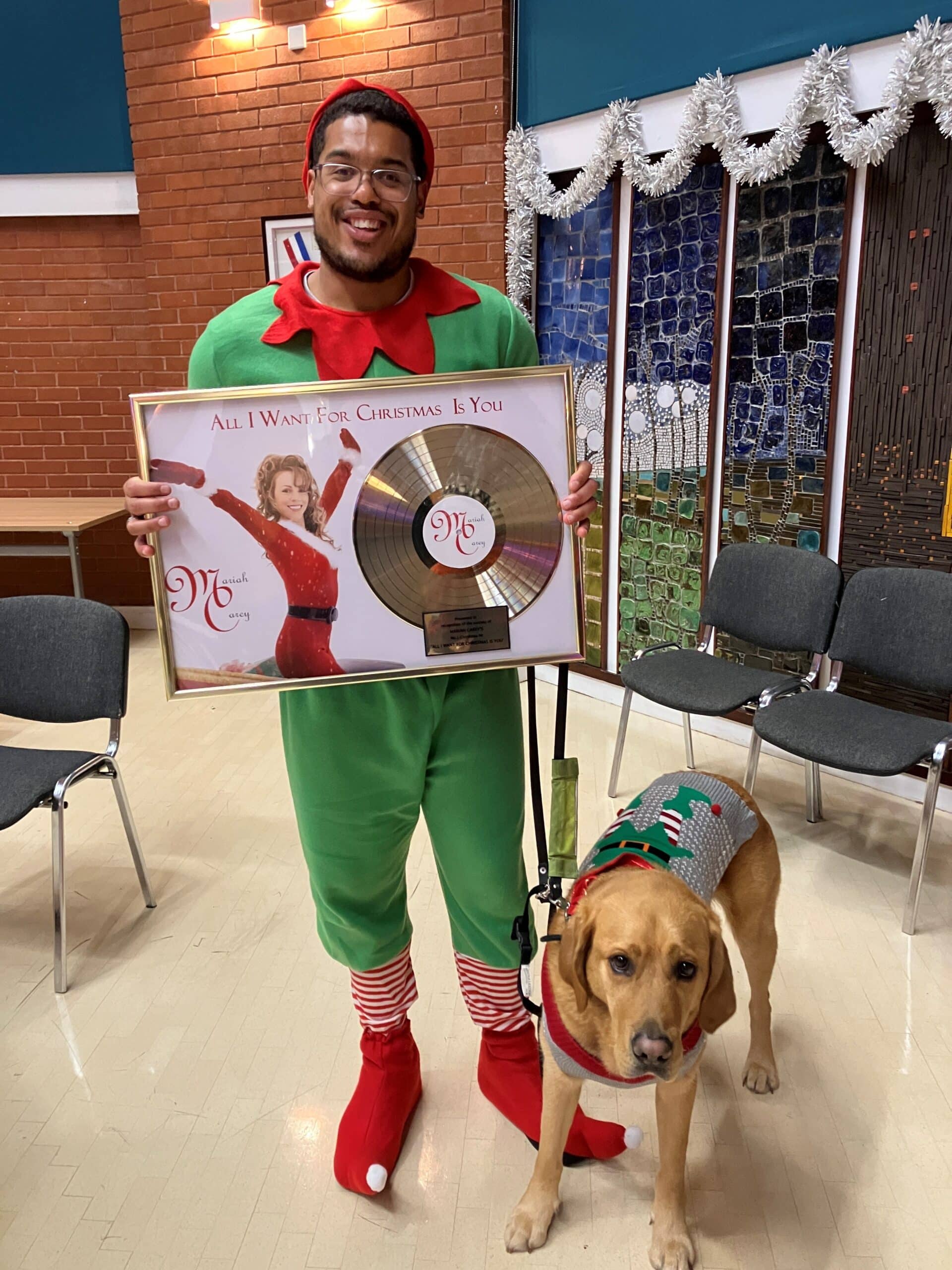 Devante dressed as an elf holding up a record